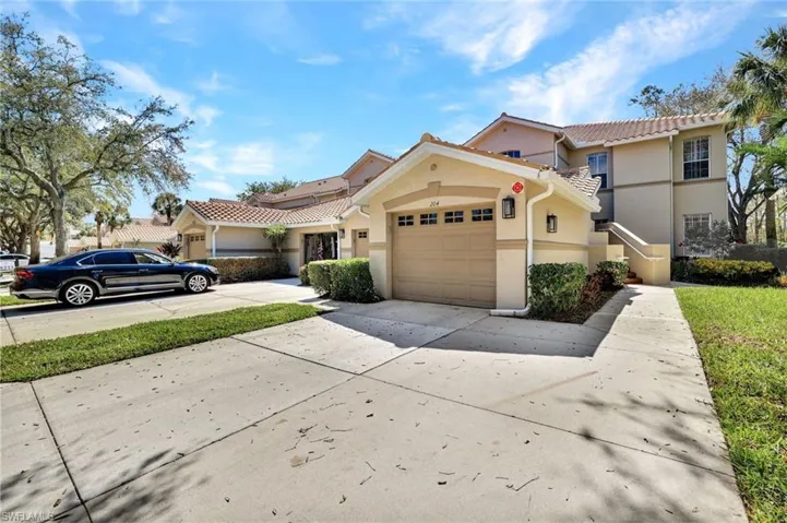 View of front of home featuring a garage, a tile roof, concrete driveway, and stucco siding