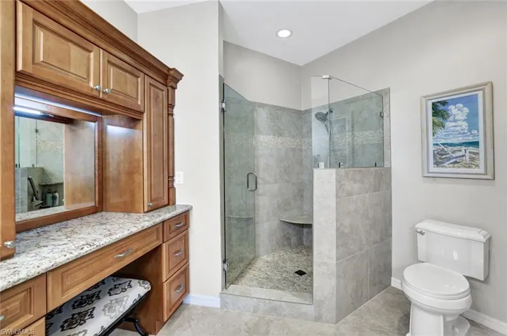 Full bathroom featuring a stall shower, baseboards, vanity, and toilet