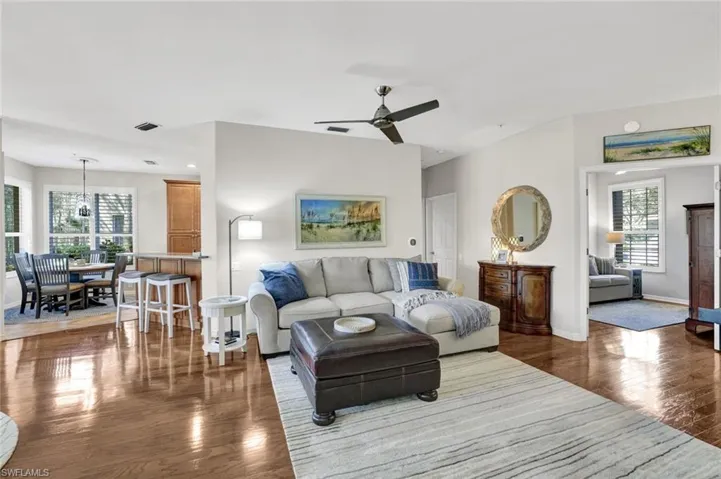Living room with a ceiling fan, visible vents, baseboards, and wood finished floors