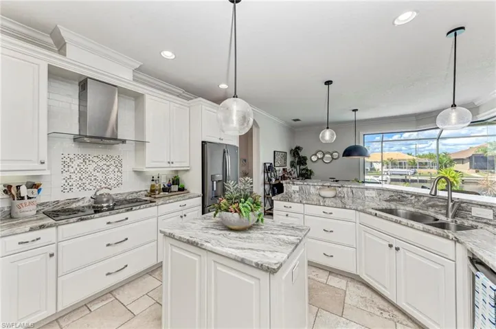 Kitchen featuring appliances with stainless steel finishes, sink, white cabinets, wall chimney exhaust hood, and a center island