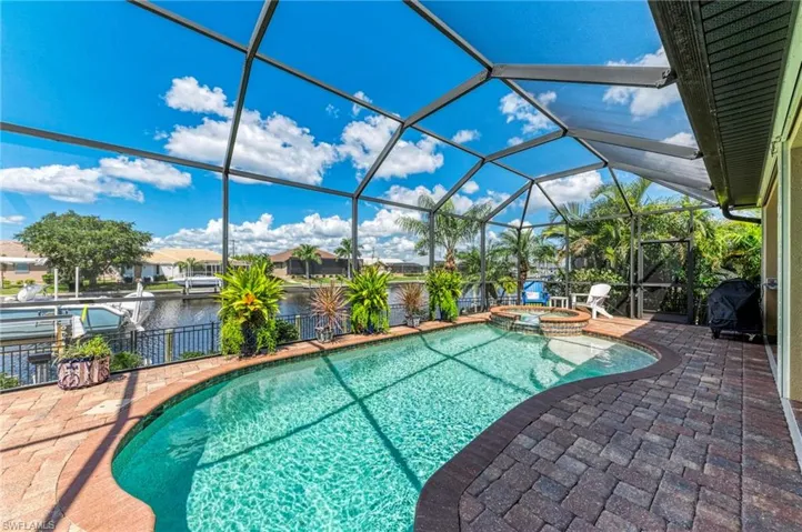 View of swimming pool featuring a lanai, a water view, a patio, and an in ground hot tub