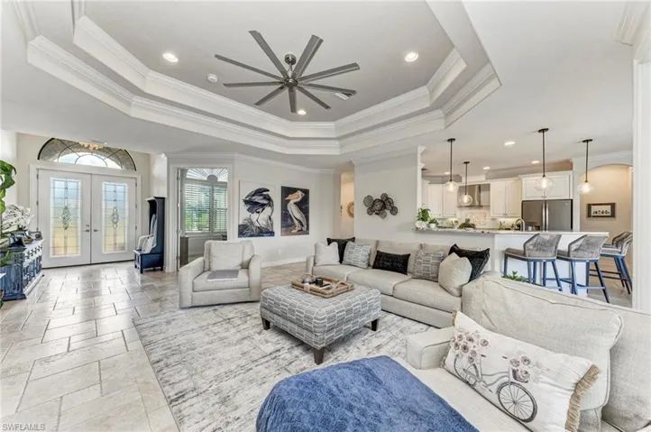 Living room with french doors, a raised ceiling, and crown molding