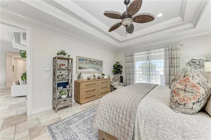 Bedroom featuring ornamental molding, a tray ceiling, and ceiling fan
