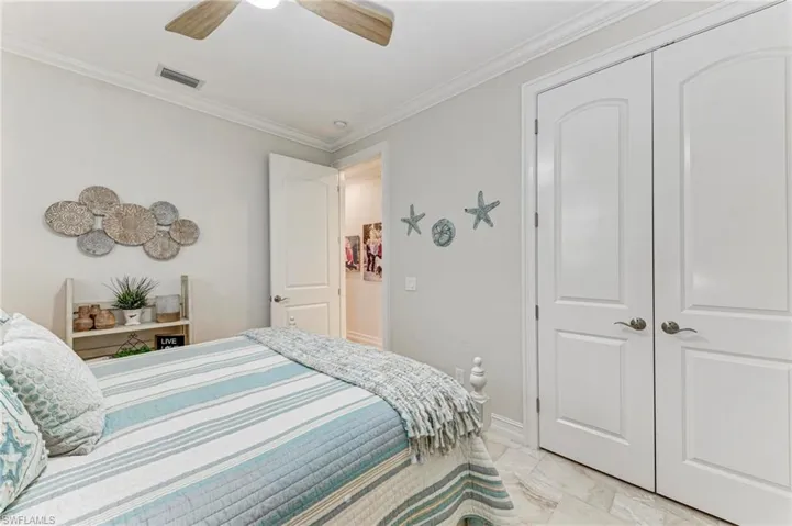 Bedroom with a closet, ceiling fan, and crown molding