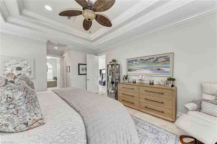Bedroom with ceiling fan, a tray ceiling, and ornamental molding