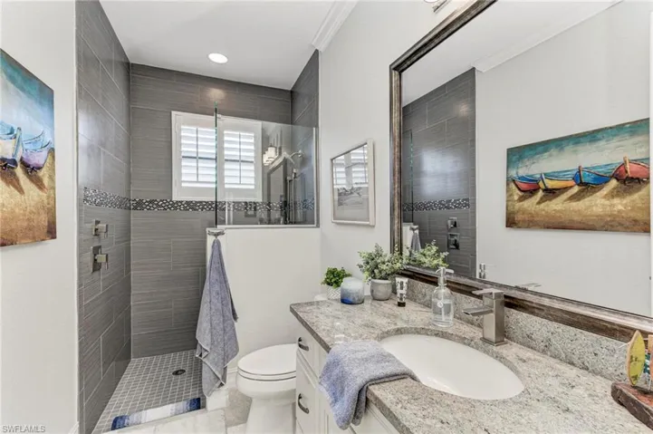 Bathroom with tile patterned floors, a tile shower, crown molding, vanity, and toilet