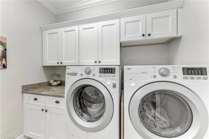Washroom with cabinets, washer and clothes dryer, and ornamental molding