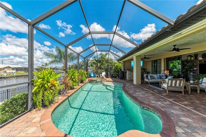 View of pool featuring a water view, outdoor lounge area, ceiling fan, a patio, and a lanai