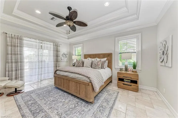 Bedroom with ornamental molding, ceiling fan, and a raised ceiling