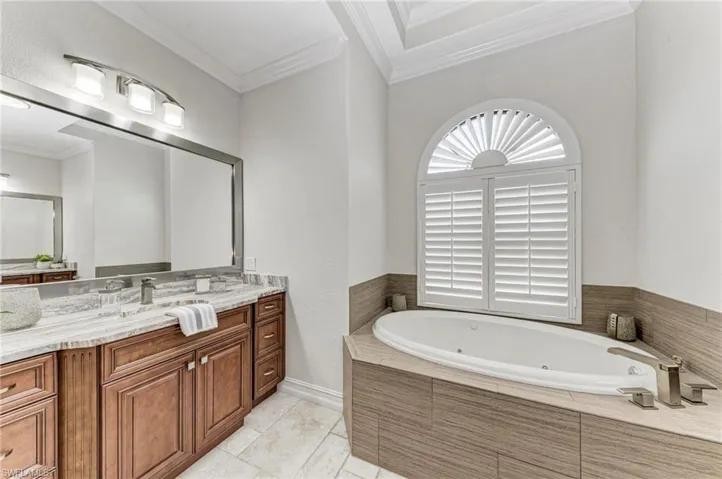Bathroom featuring a relaxing tiled tub, tile patterned flooring, vanity, and crown molding