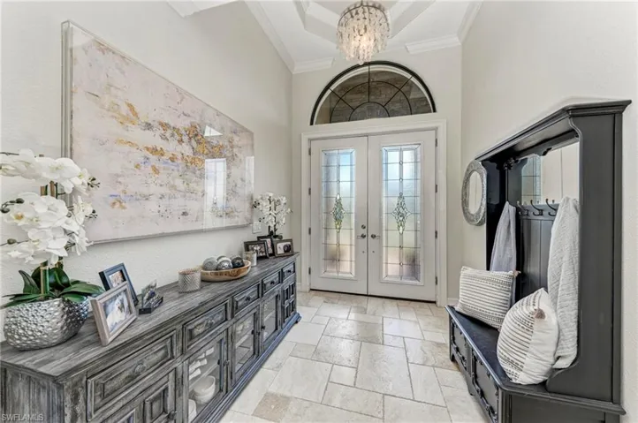 Foyer with a high ceiling, crown molding, french doors, and a notable chandelier
