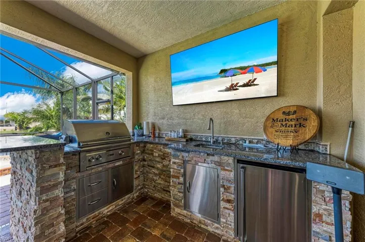 View of patio featuring glass enclosure, grilling area, area for grilling, and sink