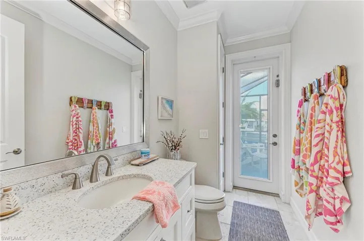 Bathroom featuring vanity, tile patterned floors, toilet, and ornamental molding