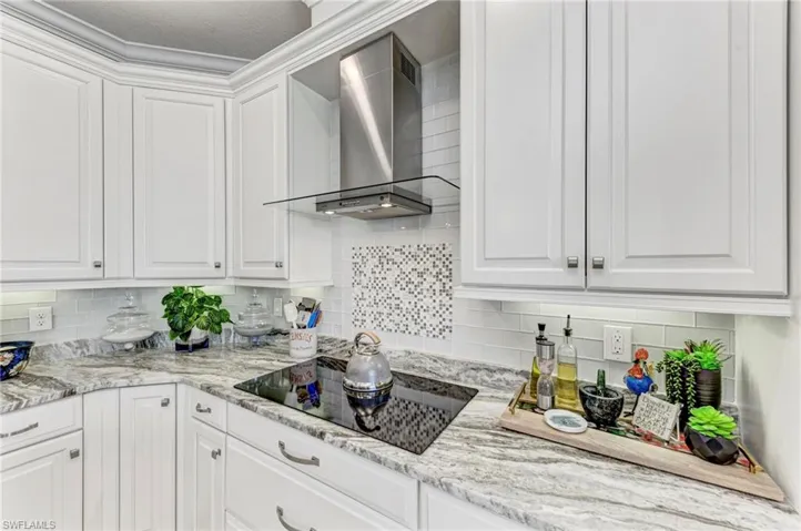 Kitchen with white cabinets, wall chimney exhaust hood, a textured ceiling, and black electric stovetop