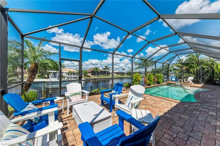 View of patio / terrace featuring a swimming pool with hot tub, a water view, and glass enclosure