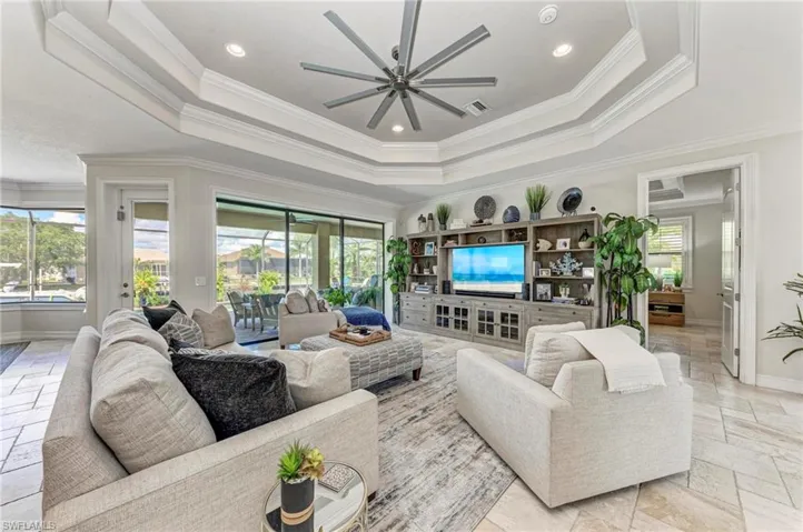 Living room with ornamental molding, ceiling fan, and a raised ceiling