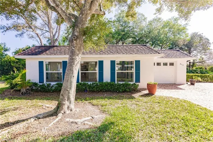 Single story home featuring stucco siding, an attached garage, a front lawn, and driveway