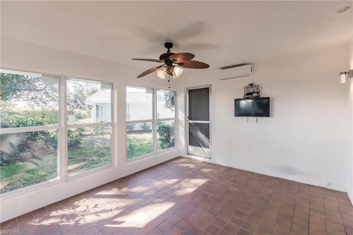 Unfurnished sunroom featuring an AC wall unit and a ceiling fan