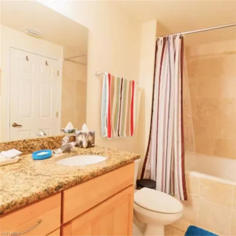 Bathroom featuring a light wood-finish vanity with a granite countertop and an undermount sink