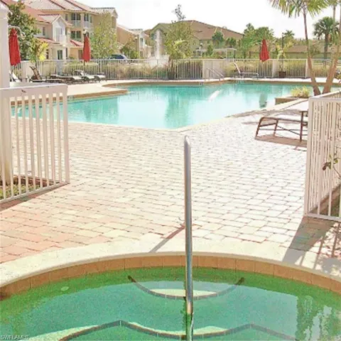 Resort-style pool area featuring a large swimming pool, a separate spa, and extensive paver decking