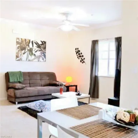 Living area featuring light-toned tile flooring, crown molding, and a ceiling fan