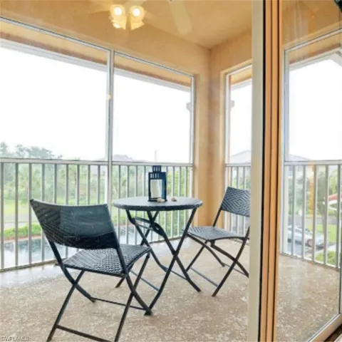 Screened balcony featuring a ceiling fan, light-toned textured flooring, and a sliding glass door