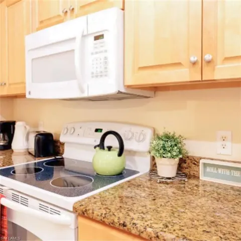 Kitchen featuring a built-in microwave, light wood cabinetry, electric range, and granite-style countertops