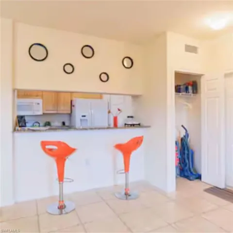 Kitchen featuring a breakfast bar with stone-finish countertop, wood cabinetry, and white appliances