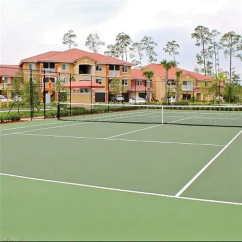 Green tennis court with white line markings and a black net