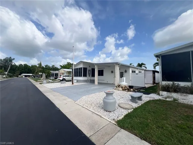 Back of property featuring driveway, a carport, and a sunroom