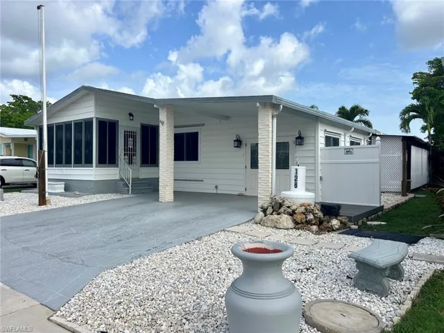 Manufactured / mobile home featuring driveway, entry steps, a carport, and a sunroom