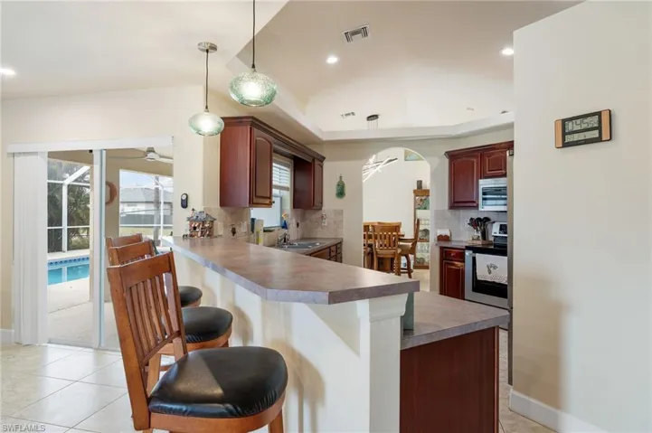 Kitchen featuring appliances with stainless steel finishes, sink, kitchen peninsula, ceiling fan, and a breakfast bar area