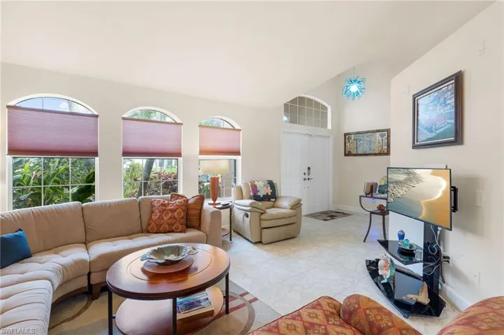 Living room with vaulted ceiling and light tile patterned flooring