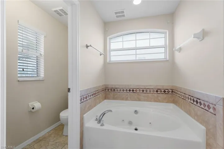 Bathroom featuring a washtub, toilet, and tile patterned floors