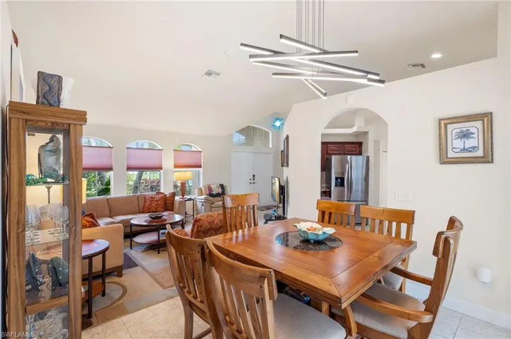 Tiled dining room featuring vaulted ceiling and a chandelier