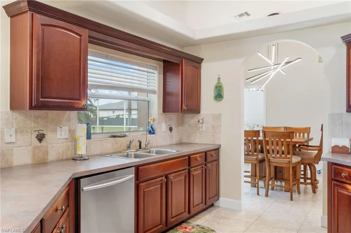 Kitchen featuring sink, tasteful backsplash, stainless steel dishwasher, and light tile patterned flooring