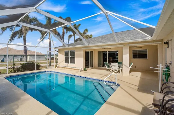 View of swimming pool featuring glass enclosure, a patio, and ceiling fan