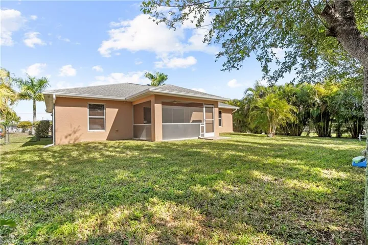 Rear view of property featuring a yard, stucco siding, and a sunroom