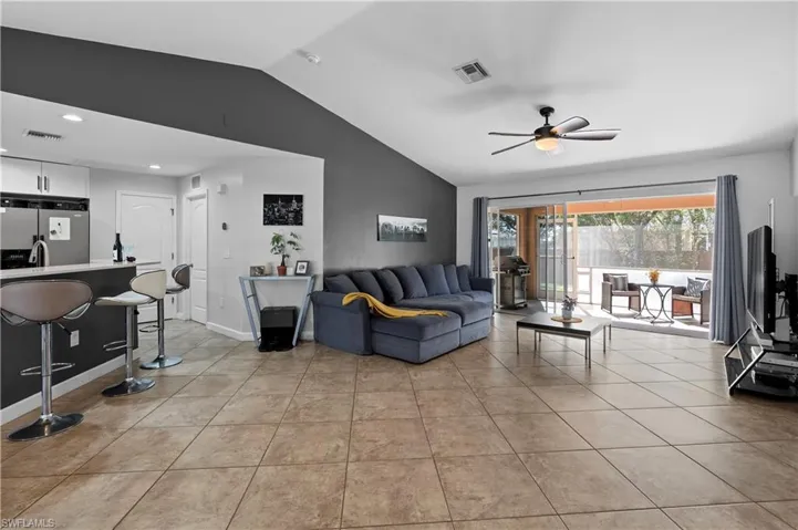 Living room featuring lofted ceiling, ceiling fan, light tile patterned floors, and recessed lighting