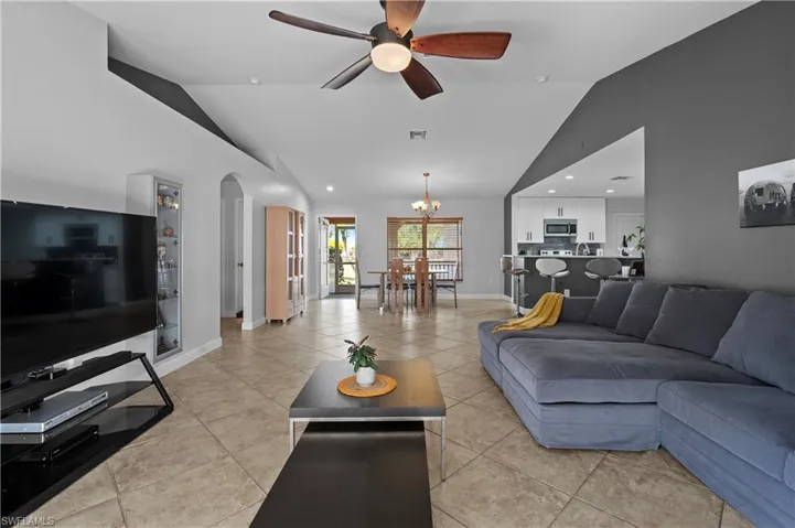 Living area with vaulted ceiling, a ceiling fan, arched walkways, a chandelier, and recessed lighting