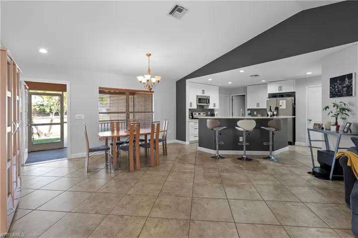 Dining area featuring recessed lighting, lofted ceiling, a chandelier, and light tile patterned floors