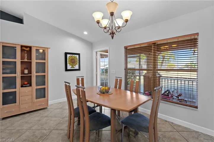 Dining area featuring vaulted ceiling, light tile patterned flooring, a chandelier, and recessed lighting