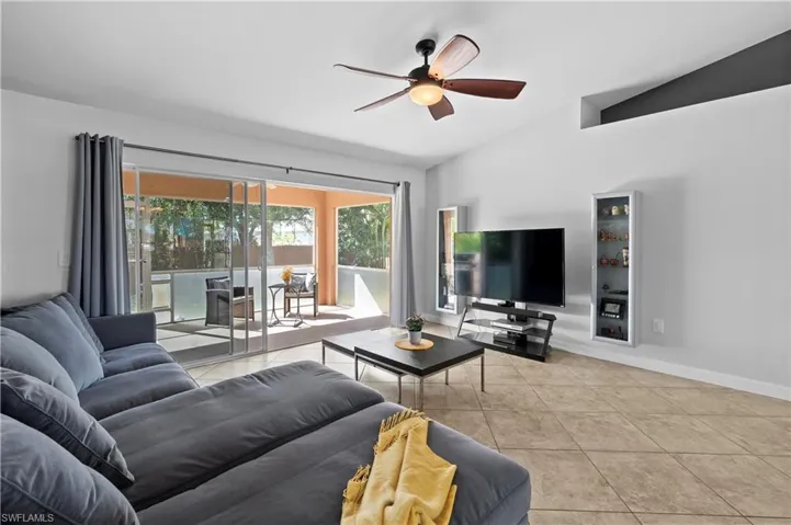 Living area featuring lofted ceiling, light tile patterned floors, and ceiling fan