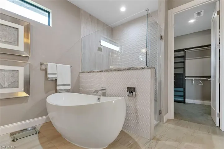 Bathroom featuring shower with separate bathtub and tile floors