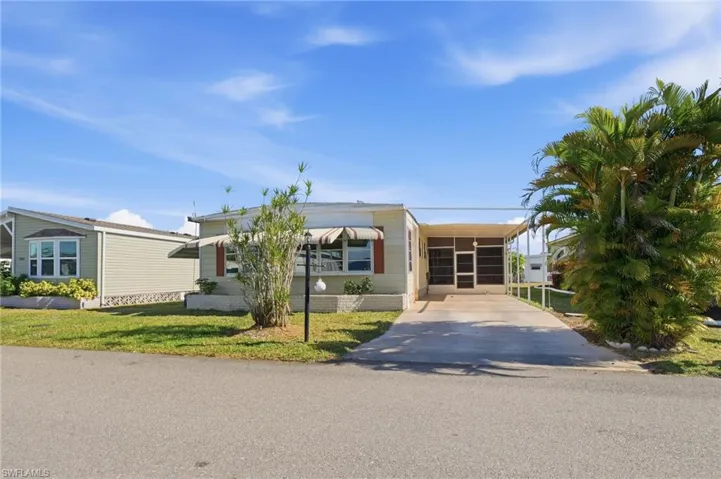 Manufactured / mobile home with driveway, a front lawn, and a carport