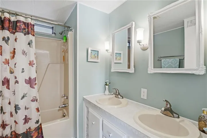 Bathroom featuring shower / bath combo and double vanity