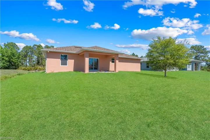 Rear view of house featuring a lawn and stucco siding