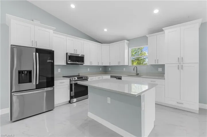 Kitchen featuring a sink, marble finish floor, appliances with stainless steel finishes, and white cabinetry