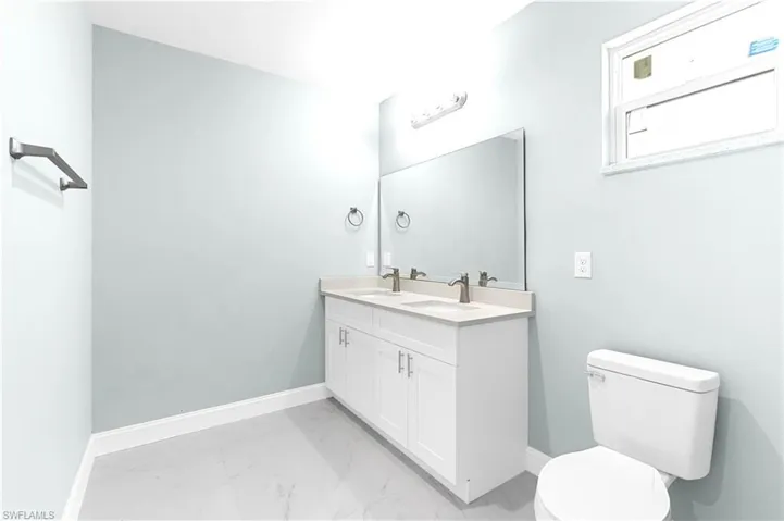 Bathroom featuring a sink, baseboards, toilet, and marble finish floor