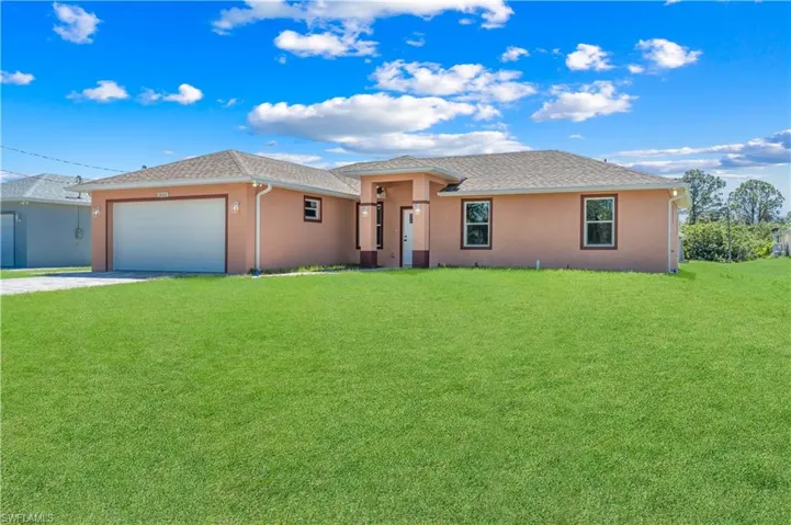 View of front of property with stucco siding, driveway, an attached garage, and a front lawn